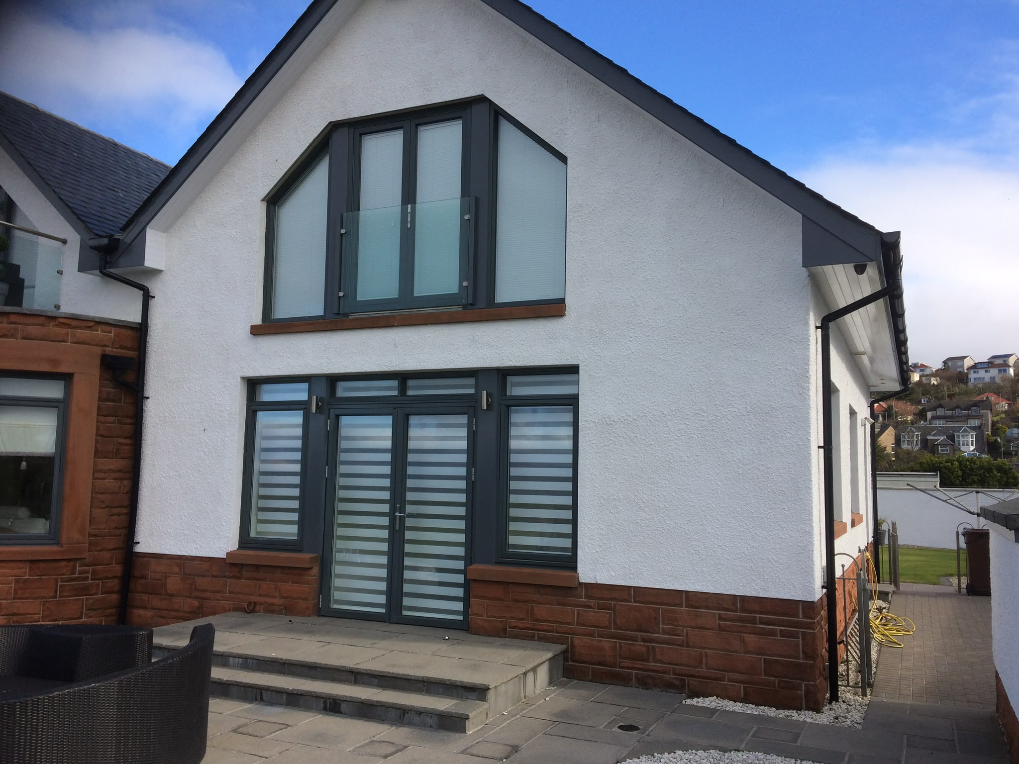 White-painted render and grey window frames on a house gable.